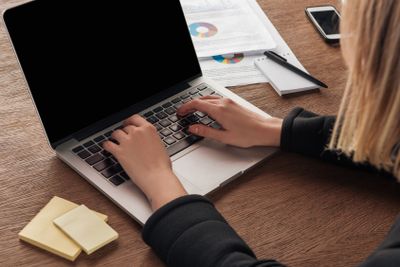 Partial view of woman typing on laptop keyboard