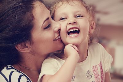 Beautiful young mother kissing her joying happy cute...