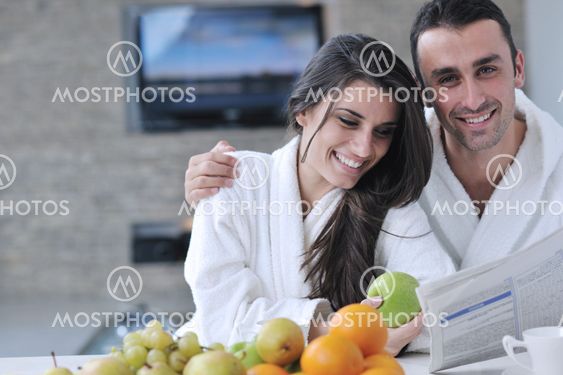 Happy couple reading the newspaper in the kitchen at breakfast