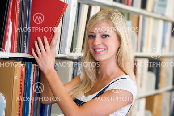 University student selecting book from library