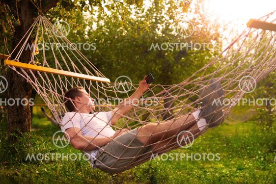 man take selfie and relax in hammock in forest in sunny...