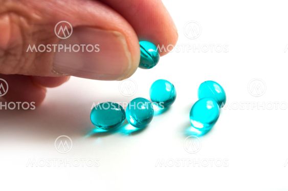 blue pills in hand on white background