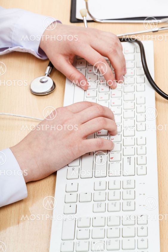 doctor works on white PC keyboard