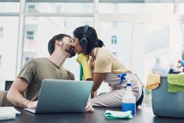 Couple, kiss or working with laptop or cleaning supplies...