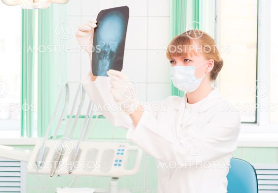 Young woman doctor looks at an X-ray of skull