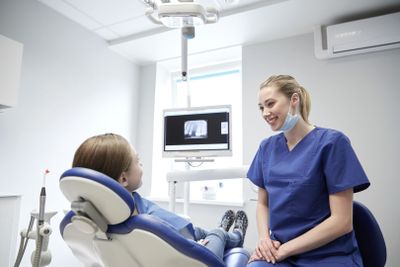 happy female dentist with patient girl at clinic