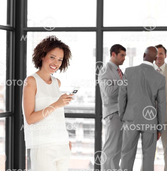 Cheerful Businesswoman holding a phone at workplace with his colleagues