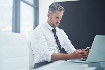 Business, man and laptop with smartphone in office for...