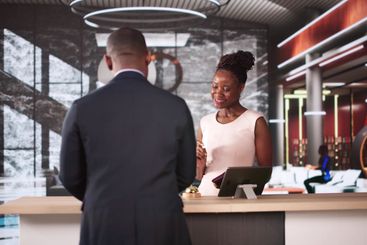 Woman At Hotel Talking To Receptionist Man