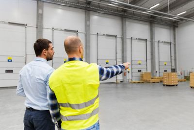 businessman showing warehouse to worker
