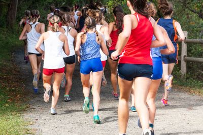 Girls cross country race on dirt path in woods taken...
