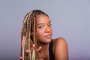 Brunette model with braids in her hair, wearing a black...