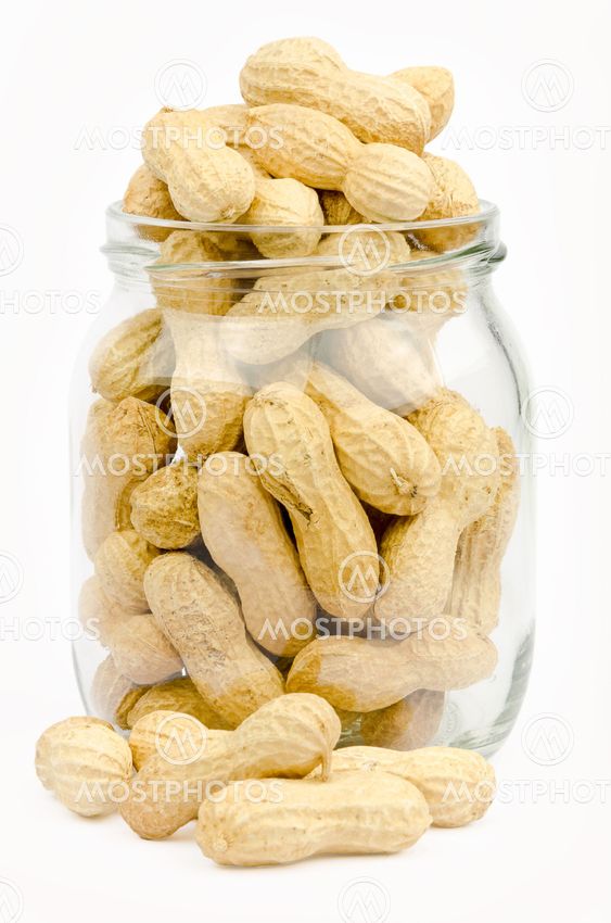 A jar full of unpeeled peanuts on a white background