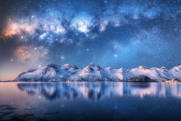 Colorful Milky Way over snowy mountains and fjord at...