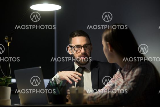 Two business people in late evening meeting.
