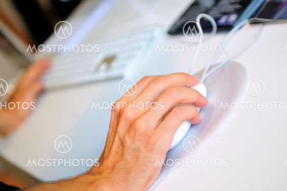 lose-up of male hand on mouse while working on laptop