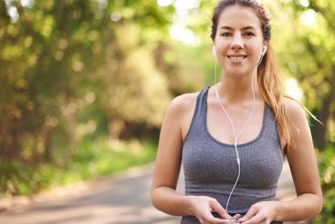Woman, earphones and outdoor for exercise in park,...