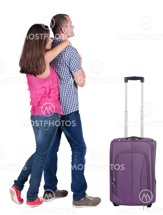Back view of young couple traveling with suitcas .