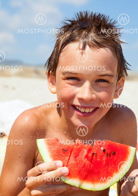 Boy eating melon on a beach