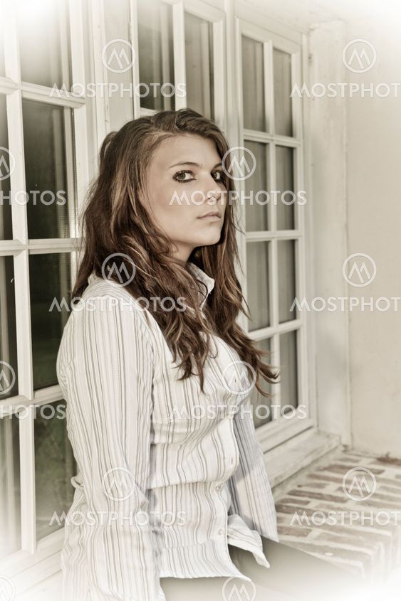 portrait of a young woman sitting on the windows in white shirt