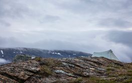 Tent by mountain under fog