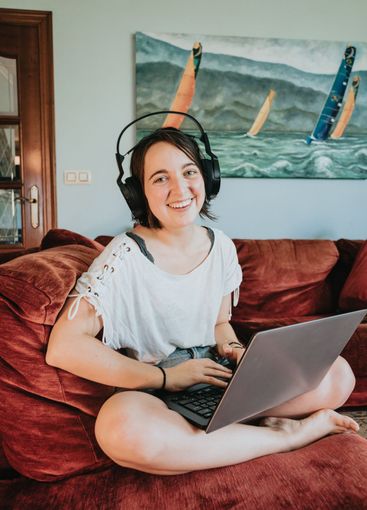 Happy young woman in a relaxed cloth works at home on a...