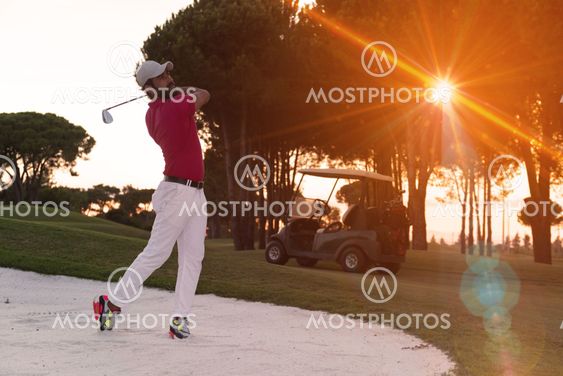 golfer hitting a sand bunker shot on sunset