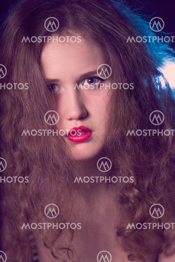 Portrait of a beautiful teen girl with long curly hairs and red lips