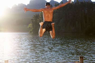 Young man jumping into lake