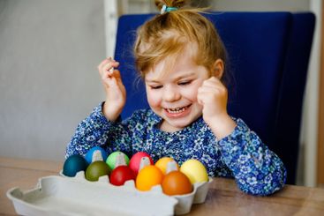 Excited little toddler girl coloring eggs for Easter....