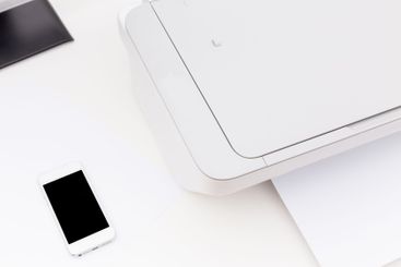 Home office setup featuring a printer, smartphone, and...