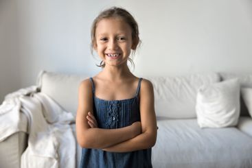Little girl standing in living room with her arms-crossed