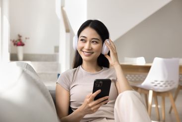 Woman listening music through wireless headphones while...