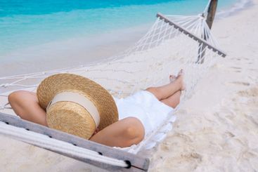 A young woman in a straw hat has her hands behind her...