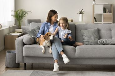 Young woman resting with little daughter and cute beagle...