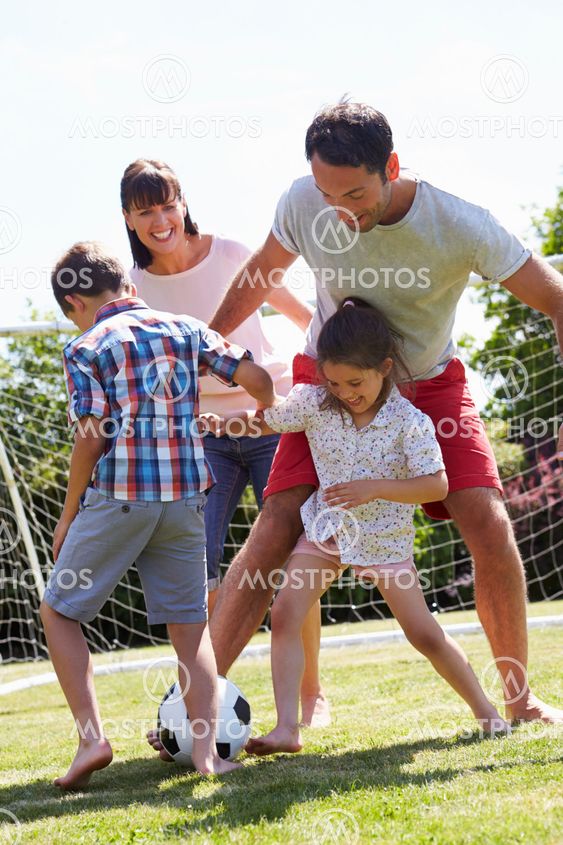 Family Playing Football In Garden Together