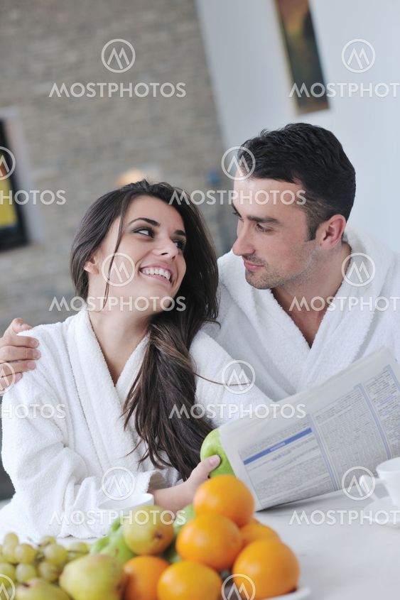Happy couple reading the newspaper in the kitchen at breakfast