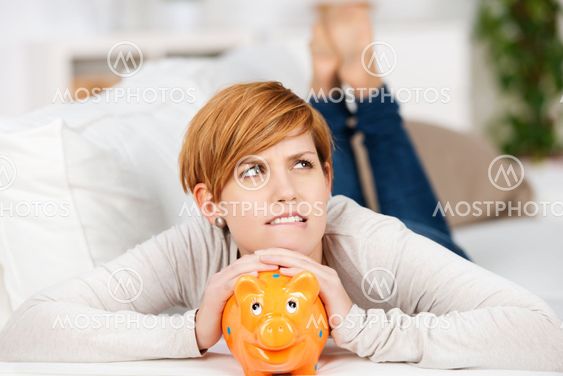 Woman With Piggy Bank While Lying On Sofa
