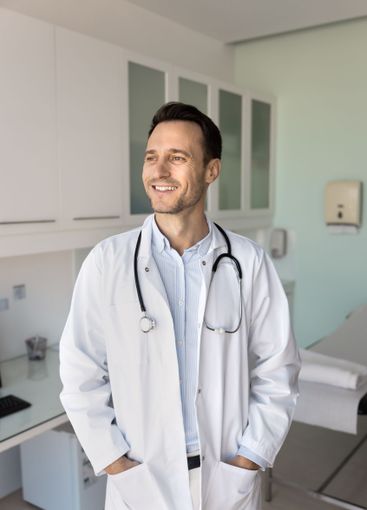 Happy young male medical specialist standing in hospital...