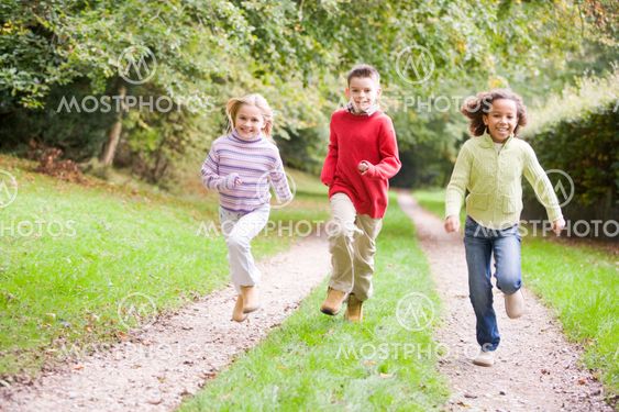 Three young friends running on a path outdoors smiling