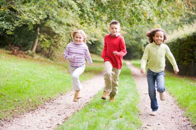 Three young friends running on a path outdoors smiling