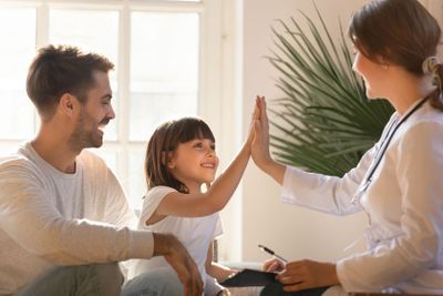 Healthy child girl giving high five to doctor celebrate...