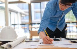 Young architect sketching house plans on a work desk in a...