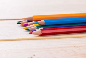 Colorful pencils arranged neatly on a wooden surface for...