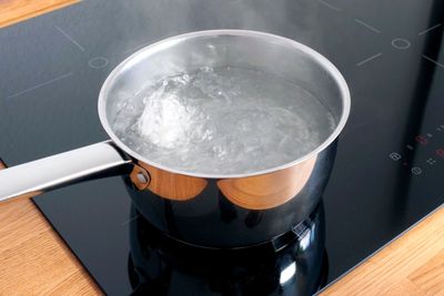 Chicken eggs boiling in stainless steel pan in water.