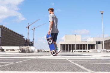 Man, skateboard and walking in urban city, rooftop and...