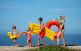 Family carries floats on sunny seaside walk vacations...