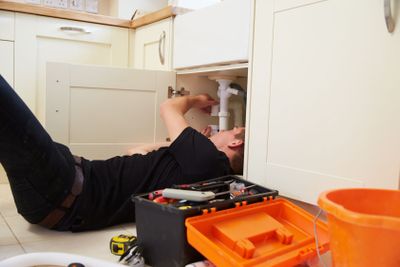 Apprentice plumber fixing the kitchen sink in a home