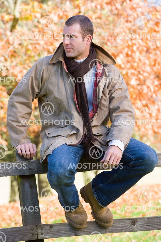 Young man sitting on fence