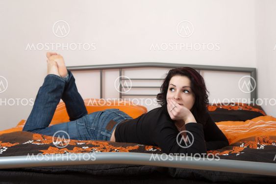 Thoughtful woman lying on bed